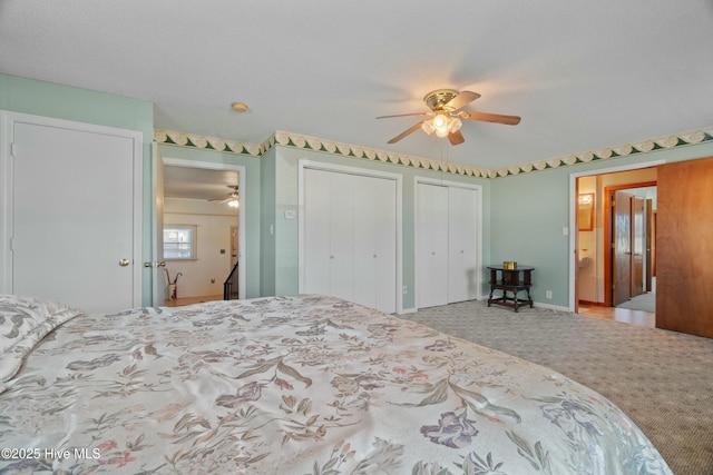 carpeted bedroom featuring ceiling fan and multiple closets