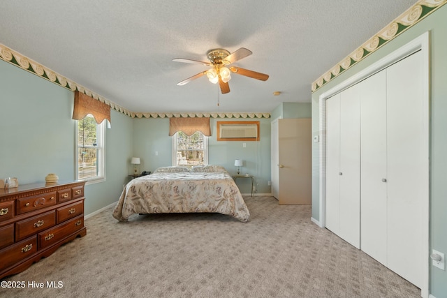 carpeted bedroom with ceiling fan, a closet, and a textured ceiling