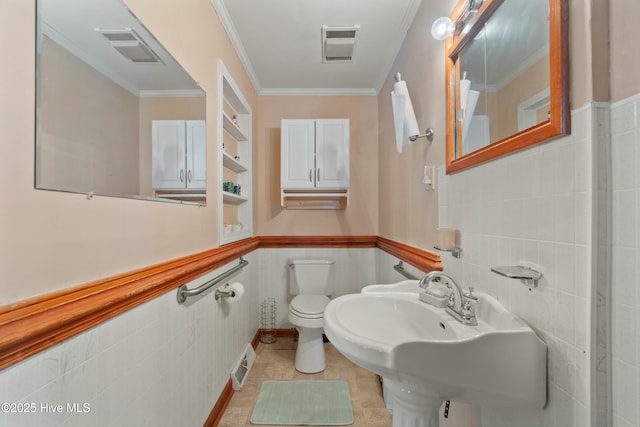 bathroom with ornamental molding, toilet, sink, and tile walls