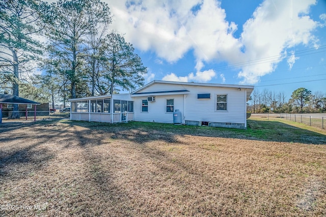 view of front of home with an AC wall unit, a sunroom, and a front yard