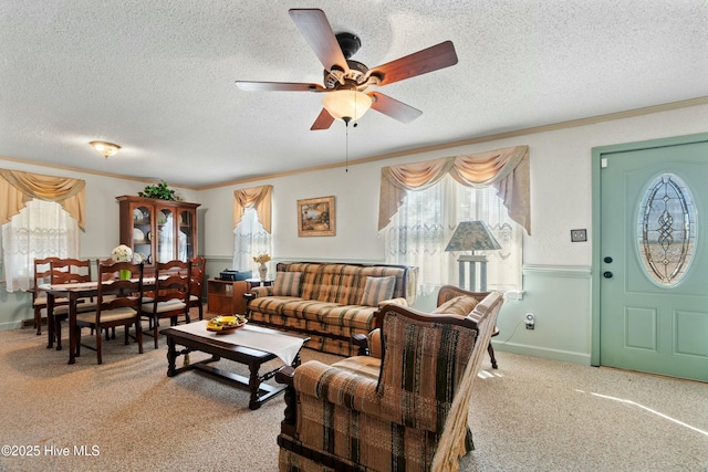 carpeted living room featuring crown molding, ceiling fan, and a textured ceiling