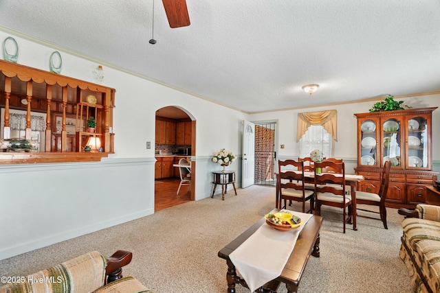 living room with crown molding, ceiling fan, light carpet, and a textured ceiling