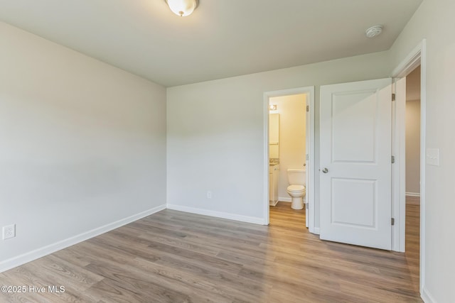 unfurnished bedroom featuring connected bathroom and light hardwood / wood-style floors