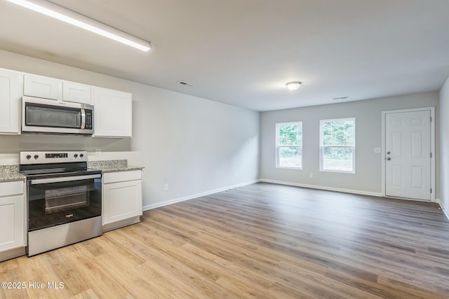 kitchen with white cabinetry, light stone countertops, stainless steel appliances, and light wood-type flooring