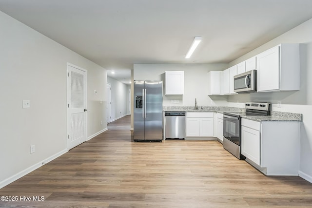 kitchen featuring stainless steel appliances, white cabinetry, and light wood-type flooring