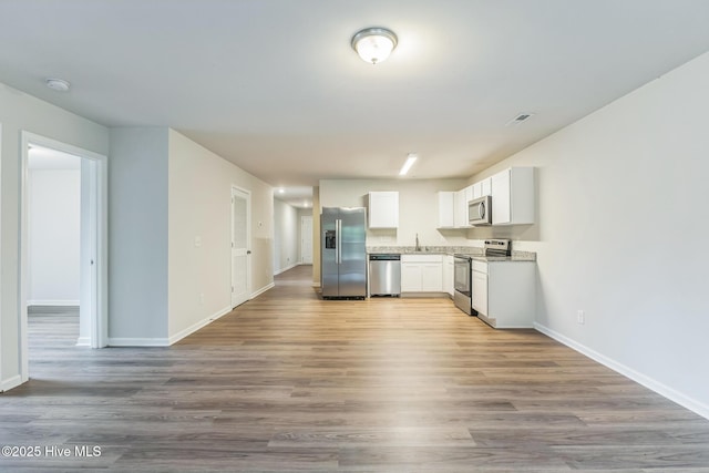 kitchen with stainless steel appliances, white cabinetry, wood-type flooring, and sink