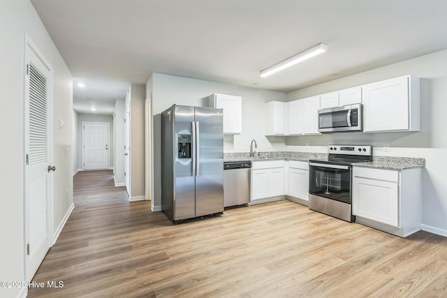 kitchen with stainless steel appliances, light stone countertops, light hardwood / wood-style floors, and white cabinets