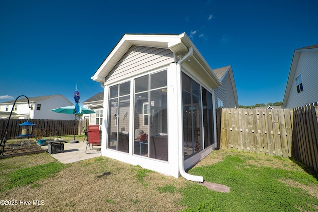 back of property with a patio, a sunroom, and a lawn