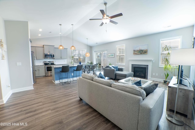 living room featuring dark wood-type flooring, lofted ceiling, a healthy amount of sunlight, and sink