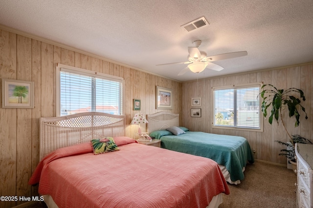 bedroom with wood walls, visible vents, and carpet flooring