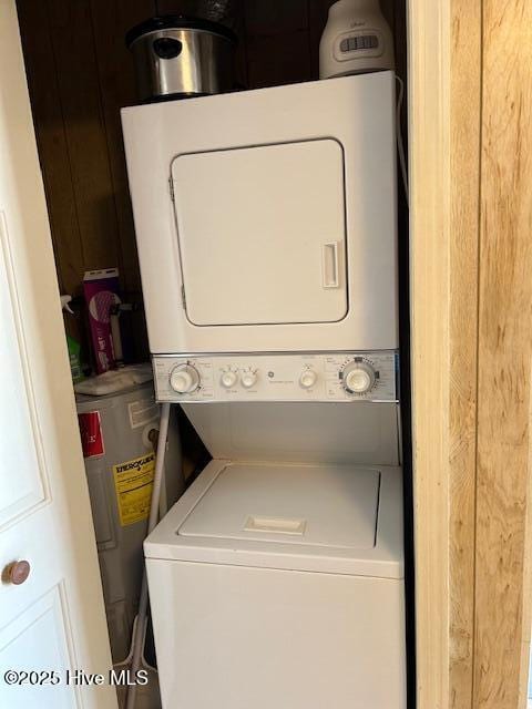 clothes washing area with laundry area, stacked washer / dryer, and electric water heater