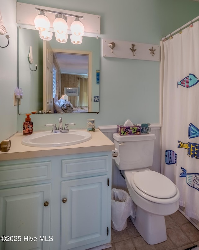 bathroom featuring tile patterned flooring, toilet, vanity, a shower with curtain, and wainscoting