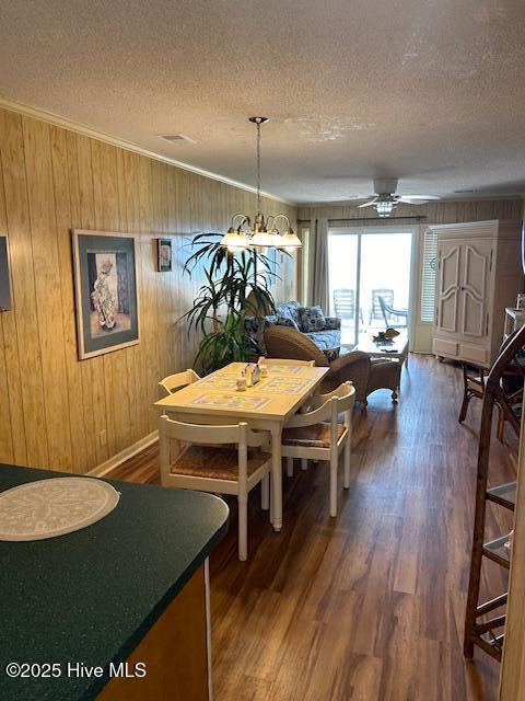 dining room featuring crown molding, a textured ceiling, wood finished floors, and ceiling fan with notable chandelier