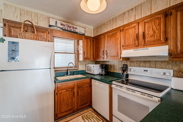 kitchen with a sink, dark countertops, white appliances, crown molding, and under cabinet range hood