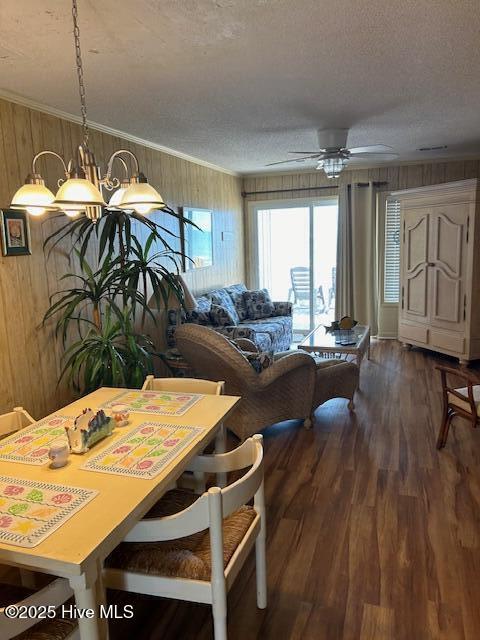 dining area featuring wood walls, crown molding, a textured ceiling, and wood finished floors