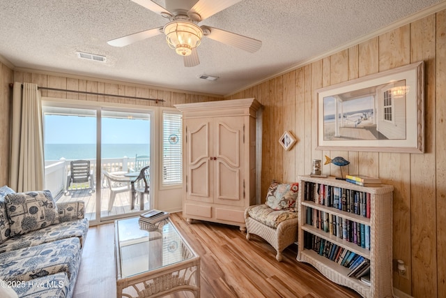living area with light wood finished floors, plenty of natural light, visible vents, and wood walls