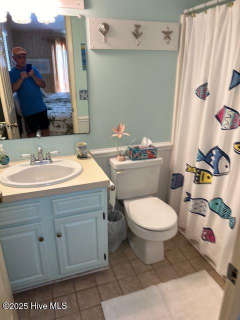 full bath with a shower with curtain, vanity, toilet, and tile patterned floors