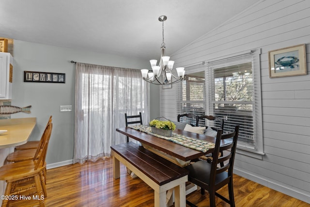 169 NW 7th St, Oak Island, NC 28465 - dining space with wooden walls, vaulted ceiling, a chandelier, plenty of natural light, and wood finished floors