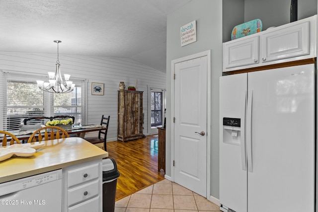169 NW 7th St, Oak Island, NC 28465 - kitchen featuring white appliances, lofted ceiling, a chandelier, white cabinetry, and pendant lighting