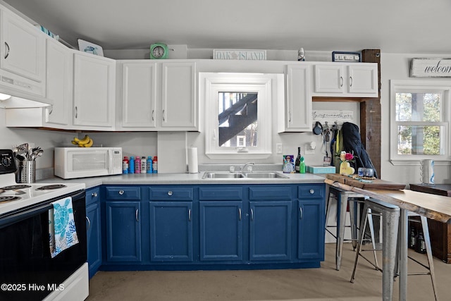169 NW 7th St, Oak Island, NC 28465 - kitchen featuring white microwave, range with electric cooktop, blue cabinets, under cabinet range hood, and a sink