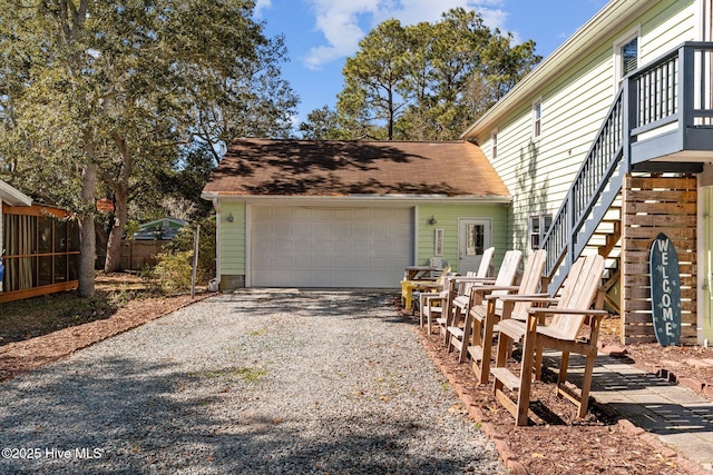 169 NW 7th St, Oak Island, NC 28465 - view of property exterior with gravel driveway, an attached garage, a shingled roof, and stairway