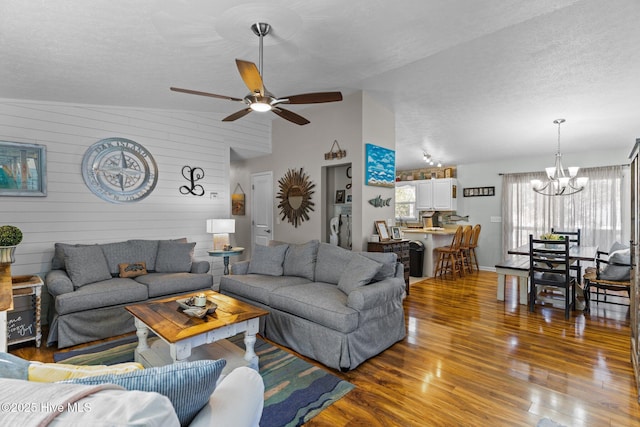 169 NW 7th St, Oak Island, NC 28465 - living area featuring a chandelier, vaulted ceiling, wood finished floors, a textured ceiling, and ceiling fan