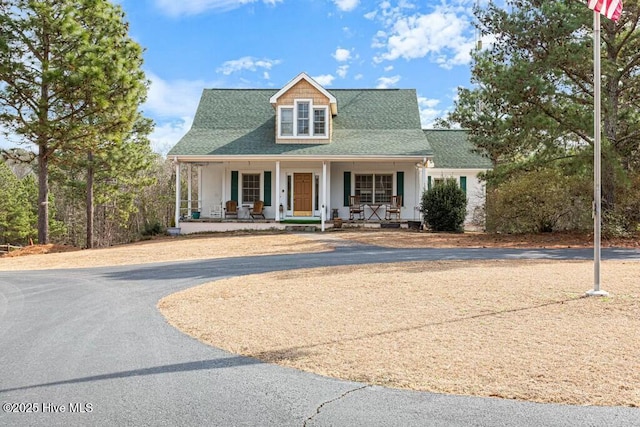 view of front of home featuring aphalt driveway, covered porch, and roof with shingles