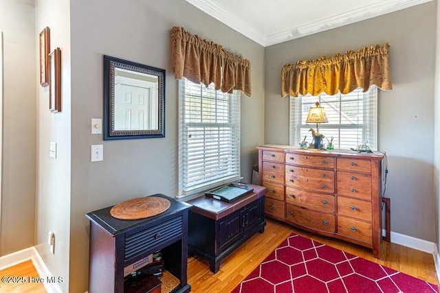 living area with baseboards, wood finished floors, and crown molding