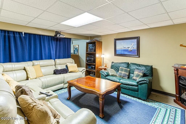 living room with a fireplace, baseboards, and a drop ceiling