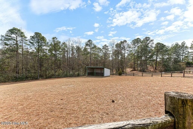 view of yard with a rural view, fence, and an outbuilding