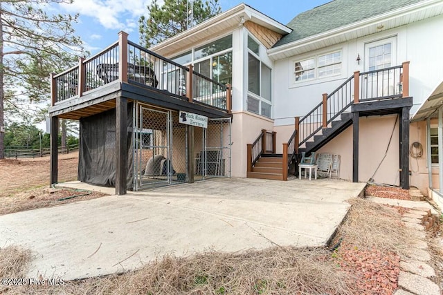 rear view of house featuring fence, stairway, and roof with shingles