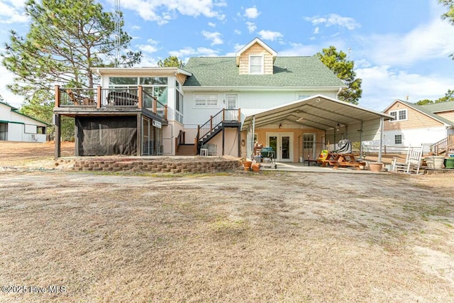 back of property featuring a shingled roof, a sunroom, a patio area, a deck, and stairs