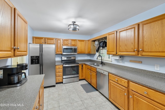 103 Ridge Rd, Hampstead, NC 28443 - kitchen featuring stainless steel appliances, a sink, light tile patterned floors, dark countertops, and brown cabinetry
