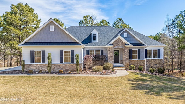 craftsman-style home featuring stone siding, a front lawn, and roof with shingles