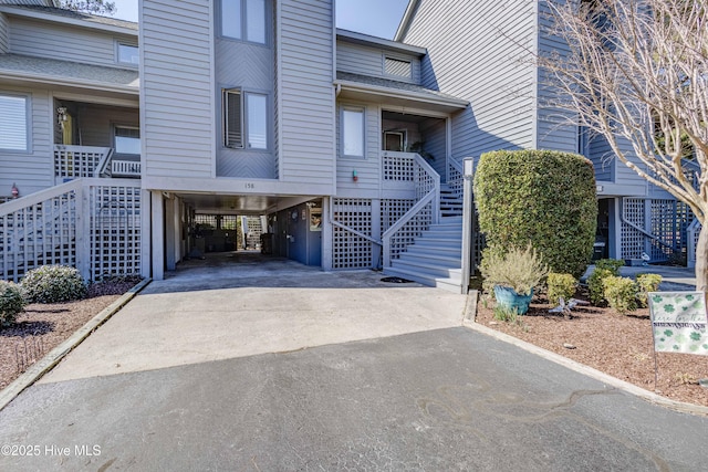 exterior space with stairway, a carport, and aphalt driveway