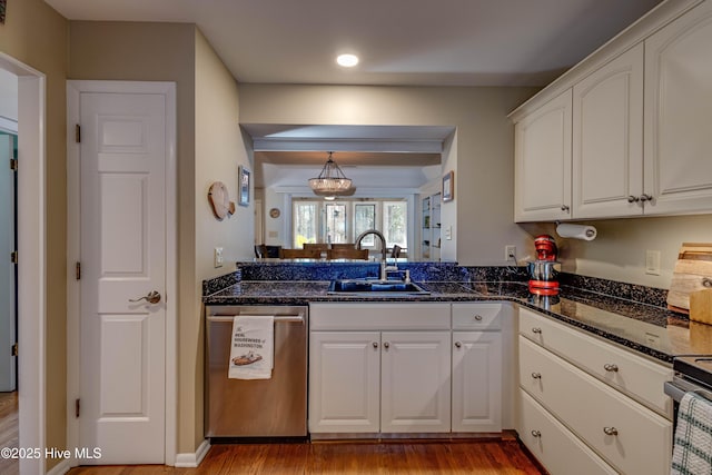 kitchen with dark stone countertops, appliances with stainless steel finishes, light wood-style floors, white cabinets, and a sink