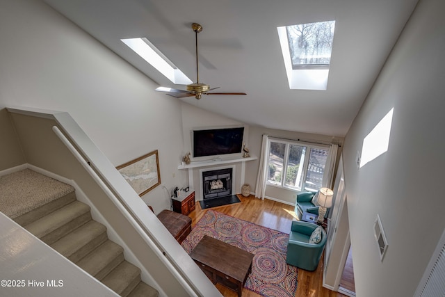 living room featuring visible vents, high vaulted ceiling, a skylight, and wood finished floors