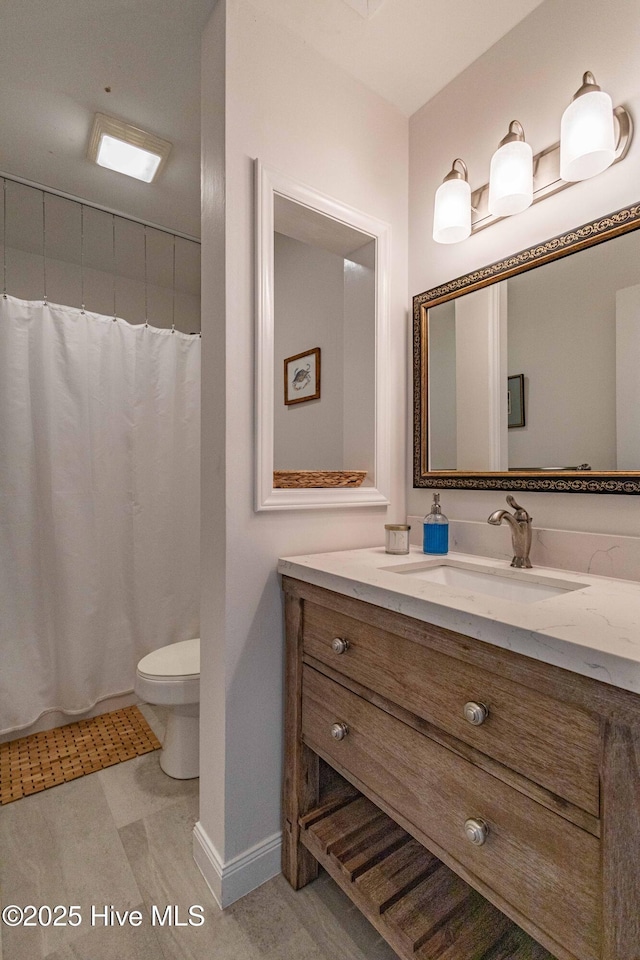 full bathroom with a shower with shower curtain, toilet, vanity, and baseboards