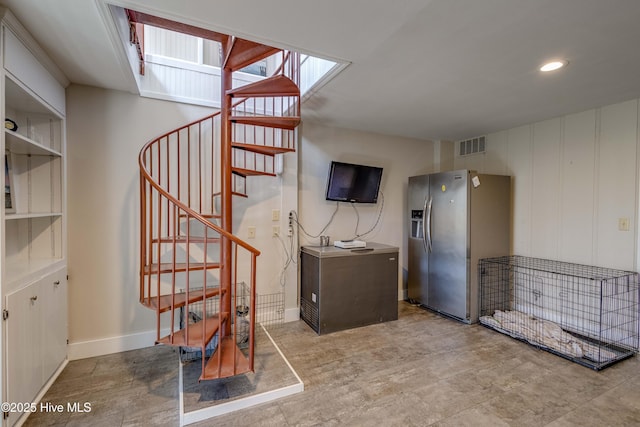 basement featuring stairway, visible vents, stainless steel fridge, and baseboards