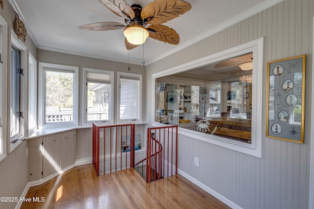 interior space with baseboards, an upstairs landing, wood finished floors, and crown molding