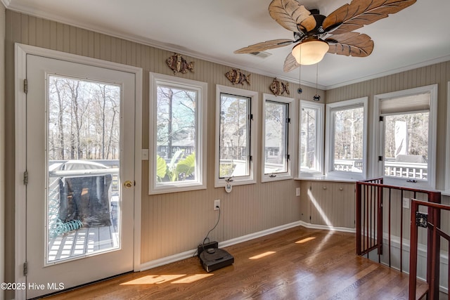 unfurnished sunroom with wood finished floors, crown molding, and baseboards