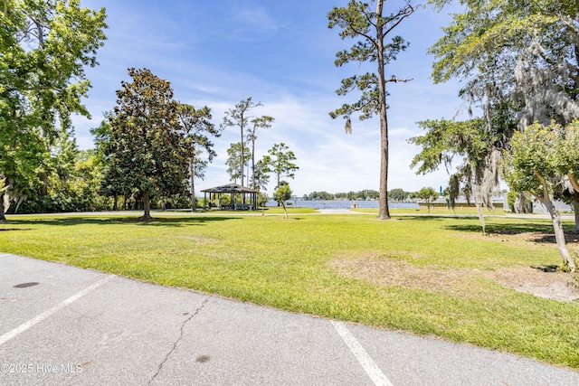 exterior space featuring a gazebo, a lawn, and a water view