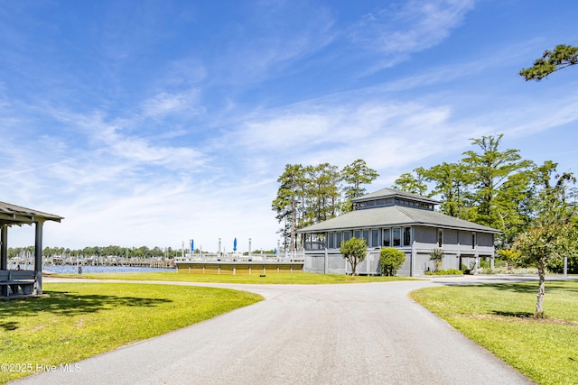 view of home's community featuring aphalt driveway, a lawn, and a water view