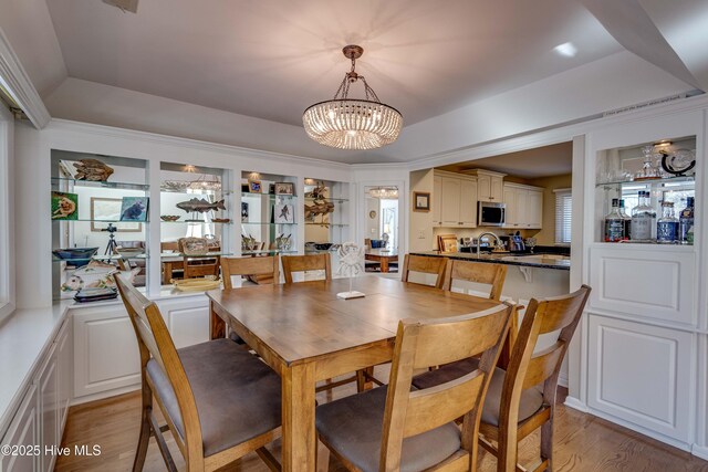 dining area featuring a raised ceiling, light wood-type flooring, and a chandelier