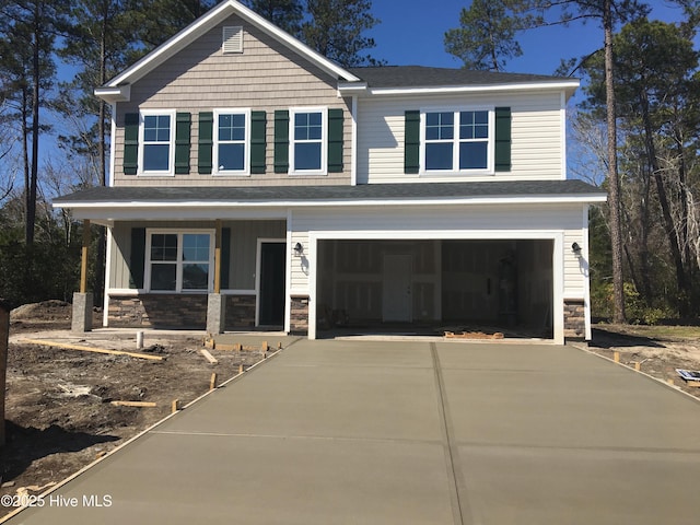 view of front of house with concrete driveway, an attached garage, covered porch, and stone siding