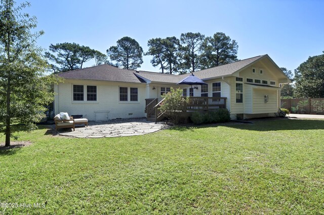 rear view of house with a lawn, a patio, fence, roof with shingles, and a wooden deck
