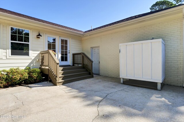 property entrance with a patio and brick siding