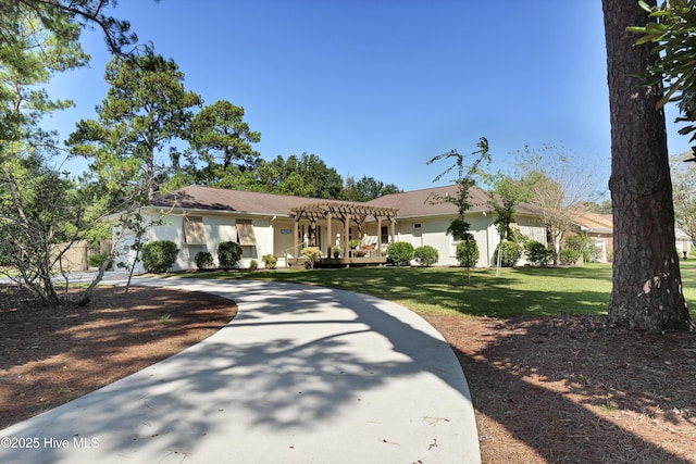 view of front of house with curved driveway, a pergola, a front lawn, and stucco siding