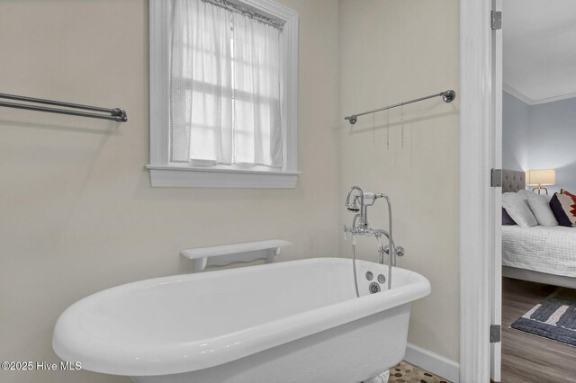 ensuite bathroom featuring a freestanding tub, connected bathroom, baseboards, and wood finished floors