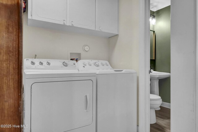laundry room featuring wood finished floors, crown molding, washing machine and dryer, and baseboards
